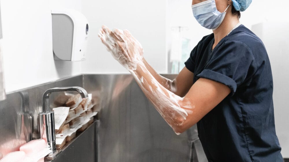 hospital staff washing hands above surgical scrub sink